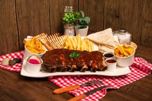 a plate of BBQ Back Ribs with fries, Tortilla, Chips, Pickles and Sauce